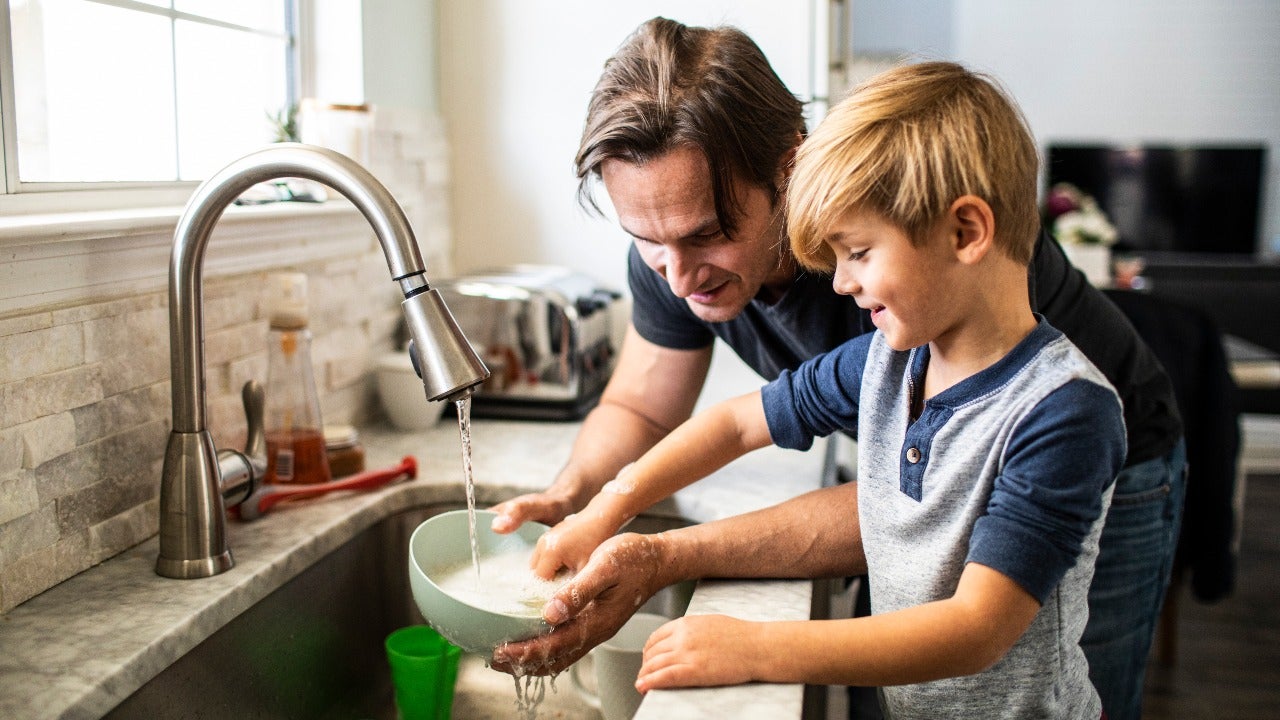 Man washes dishes with his son.