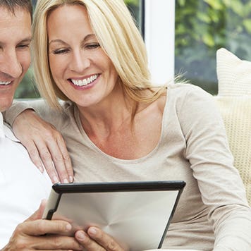 Couple sitting in sofa using tablet computer © iStock