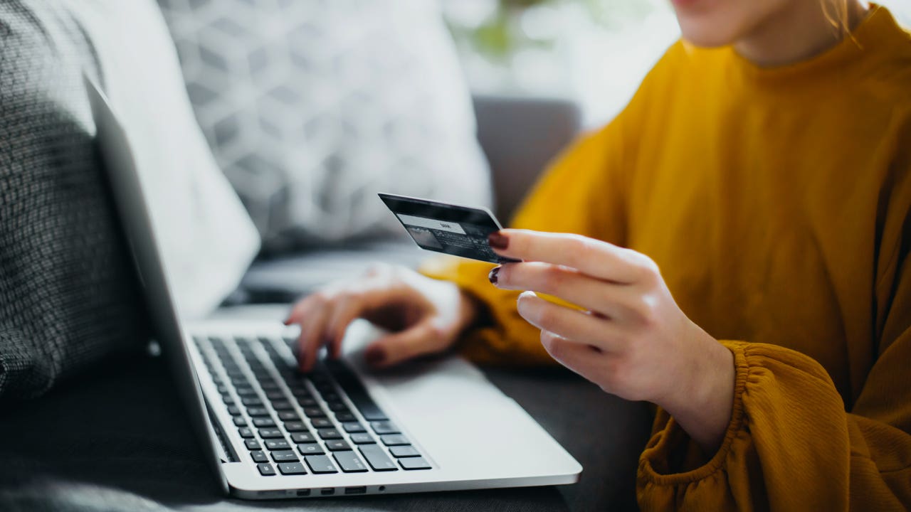 close up of hand holding credit card and typing on computer