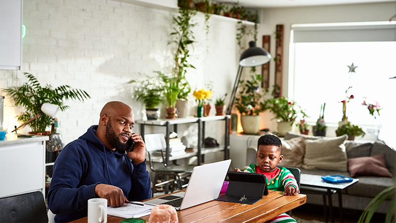 Father on phone call and working with son watching tablet