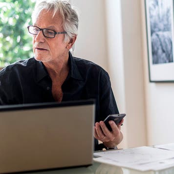 Senior man sitting in home office and using laptop