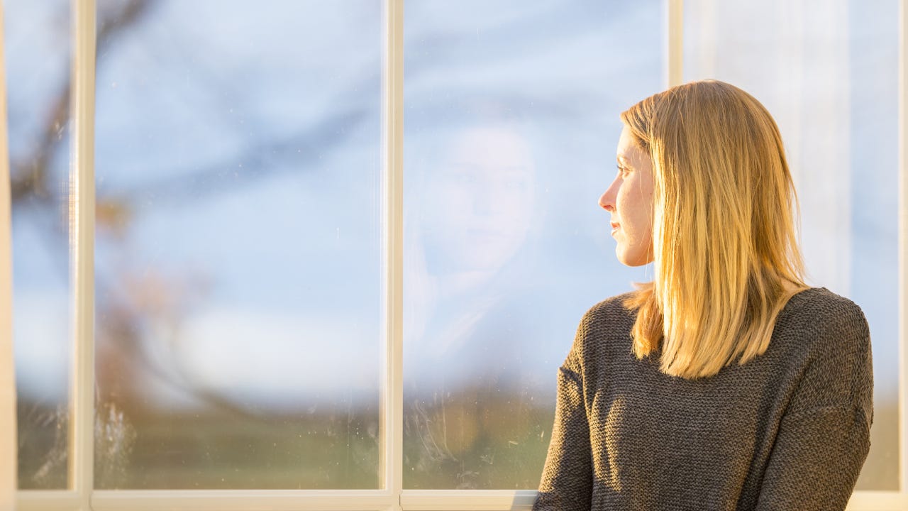 A woman sit and pensively stares out the window.