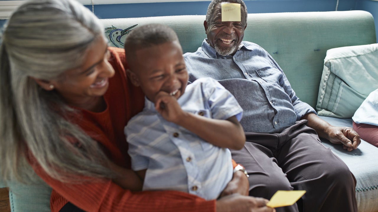 A grandson is playing with his grandparents in the living room.