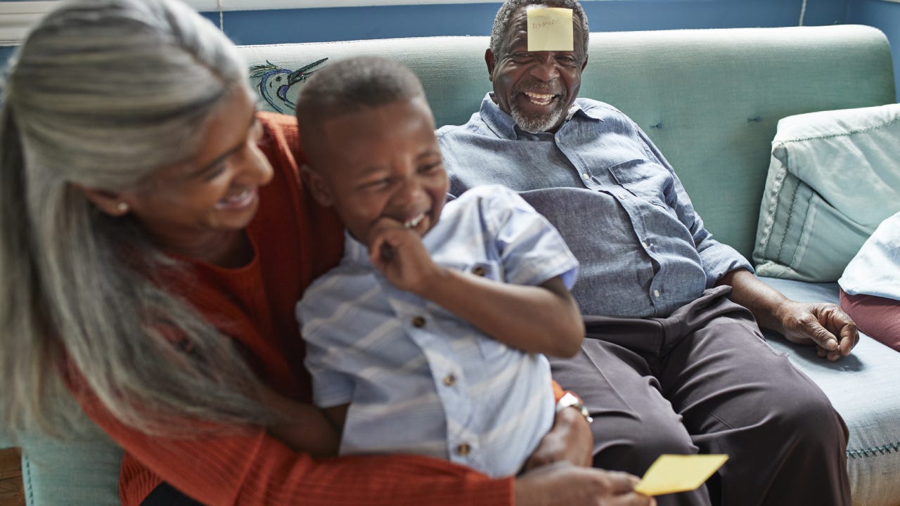 A grandson is playing with his grandparents in the living room.