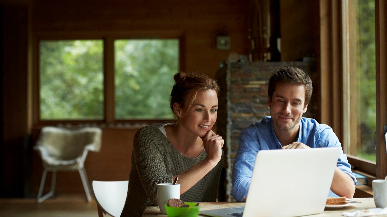 A young couple look at their laptop computer in a cottage