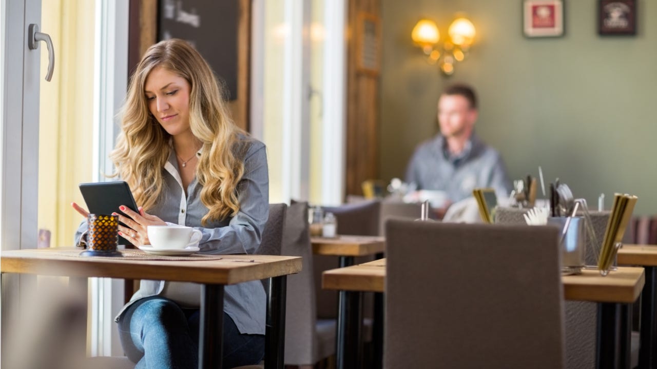 Woman works on a tablet at a cafe