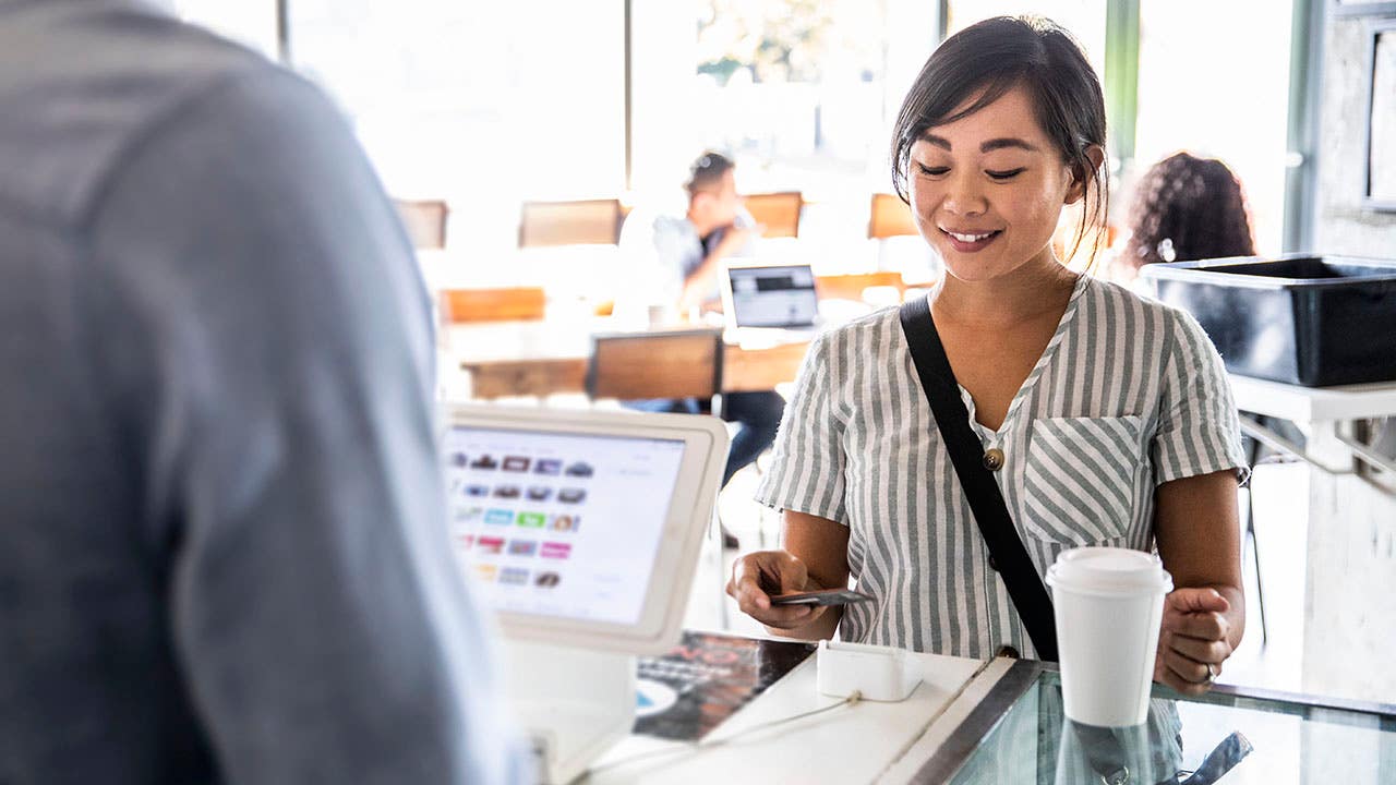 Young woman using credit card reader at coffee shop