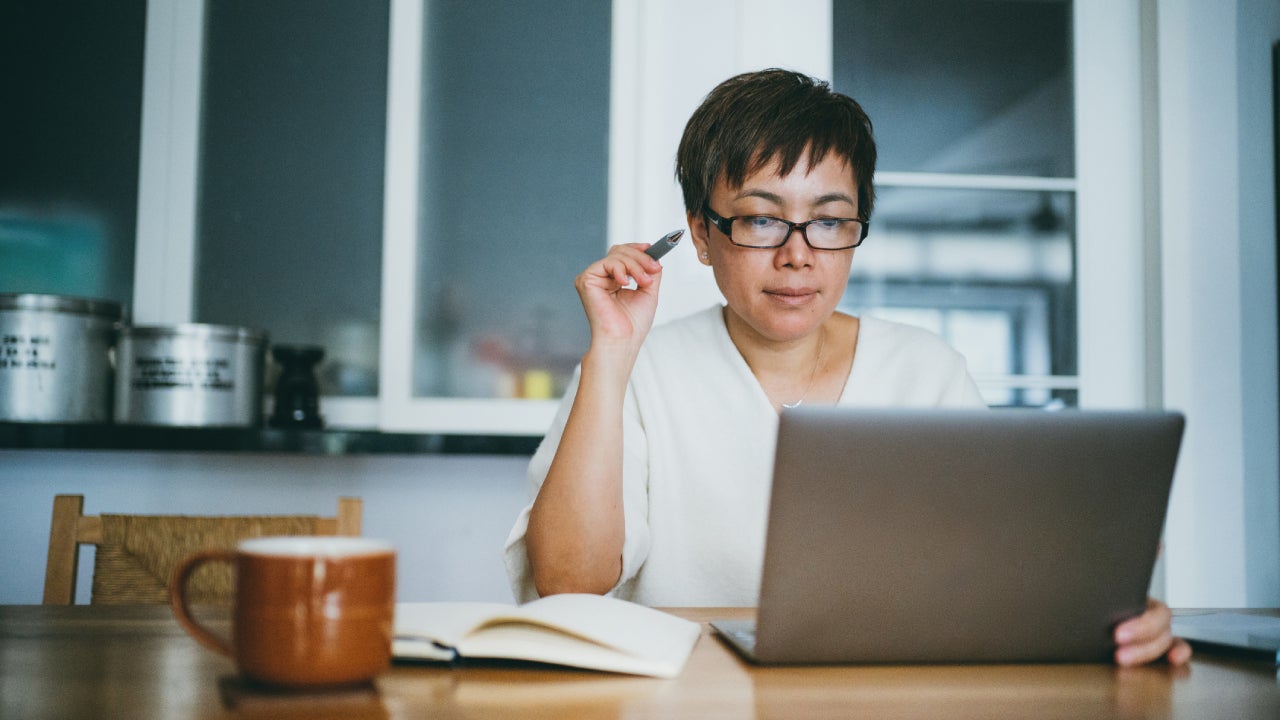Asian senior woman working on her home finance with laptop at home