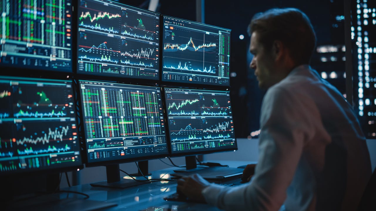 Financial Analyst Working on a Computer with Multi-Monitor Workstation with Real-Time Stocks