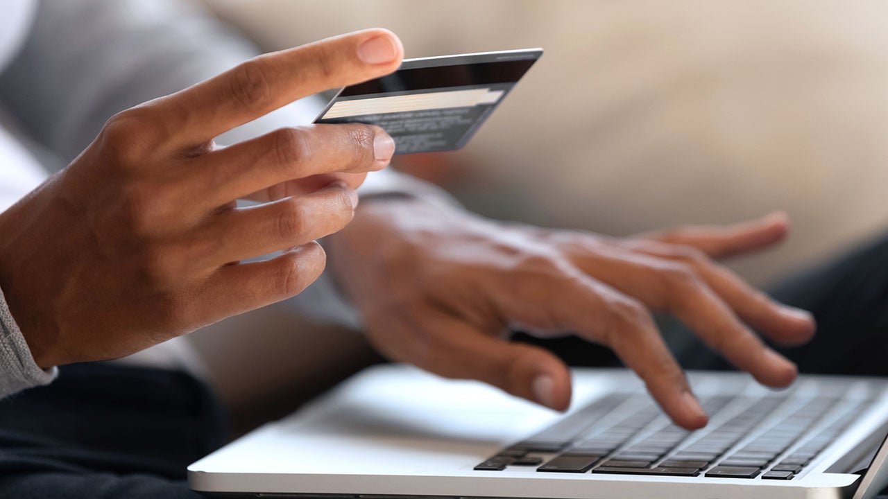 Woman holding a credit card while typing on a laptop