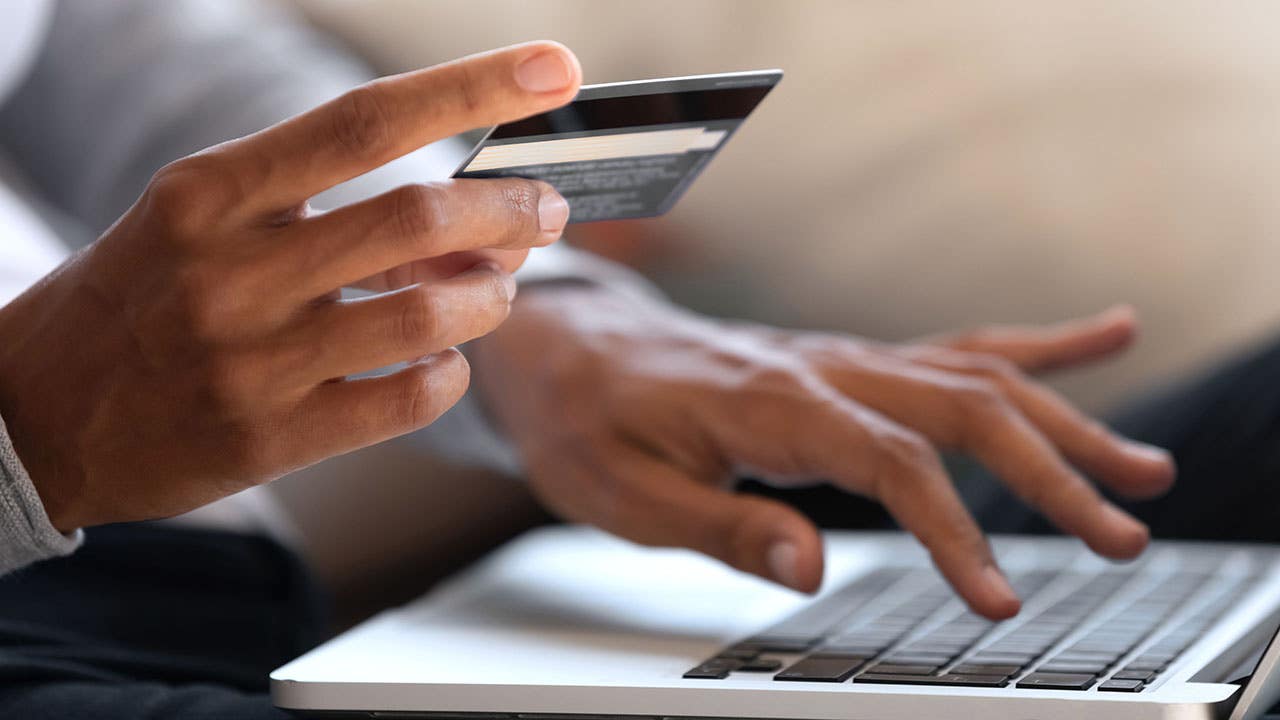 Woman holding a credit card while typing on a laptop