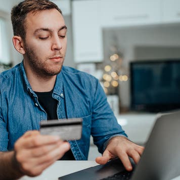 man holding credit card and shopping online at home