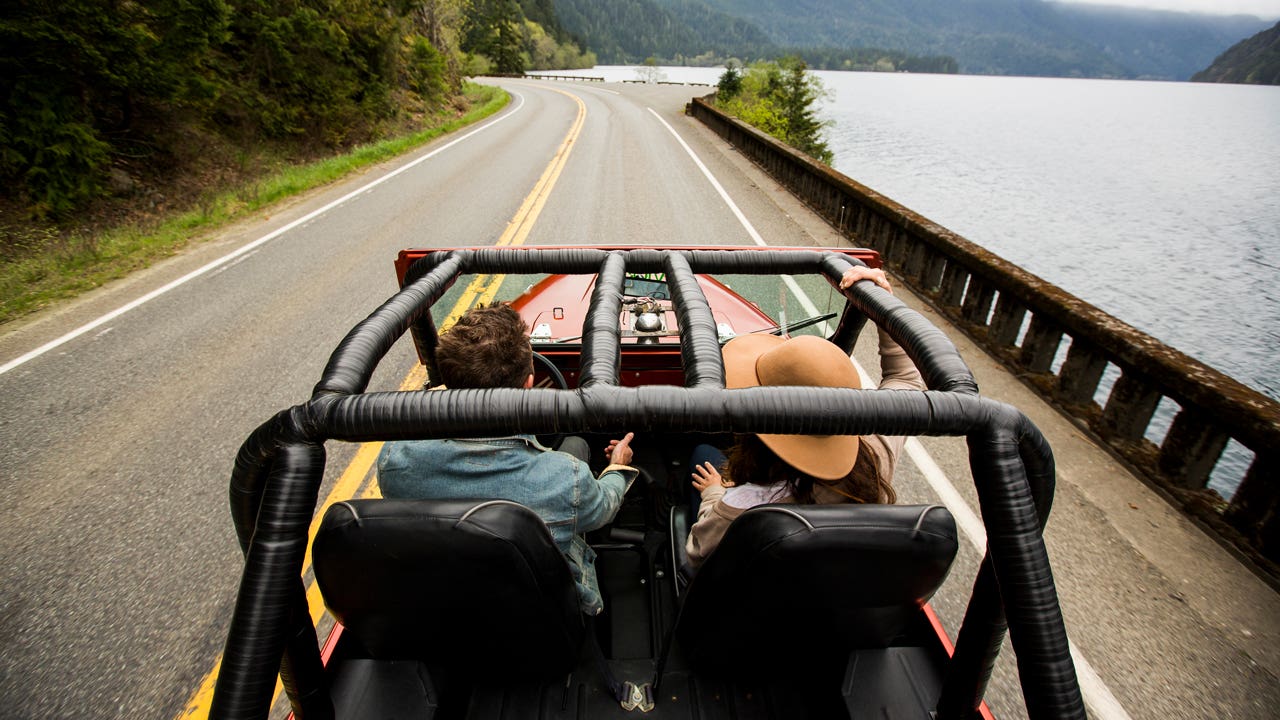 a couple in a convertible jeep driving down the road