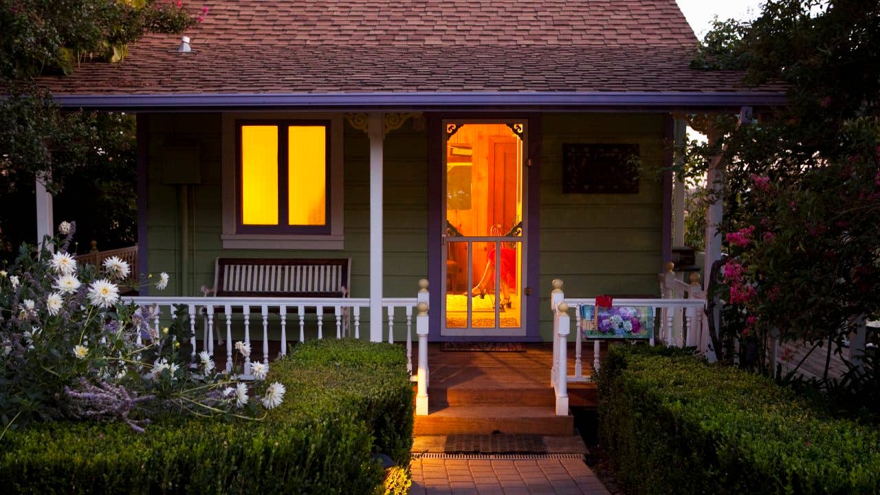 A cottage-style home with lights on in the evening