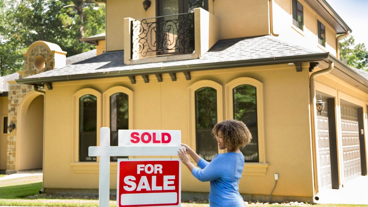 Real estate agent placing a "sold" sign on a home