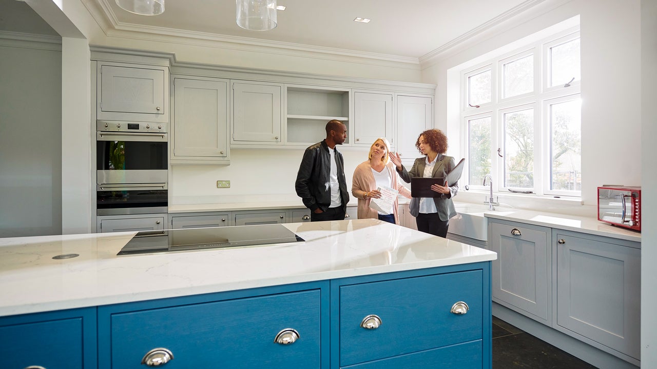couple with a realtor looking at the kitchen in a house for sale