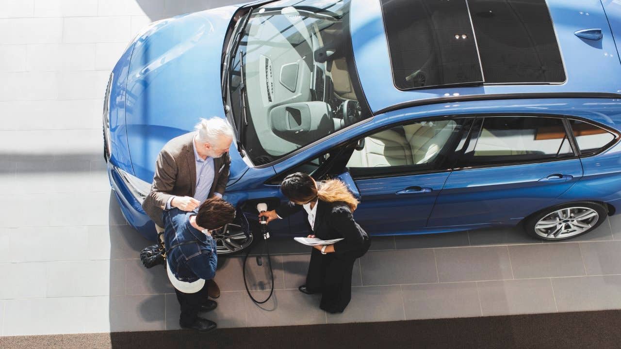 Saleswoman explaining customers to charge electric car at showroom