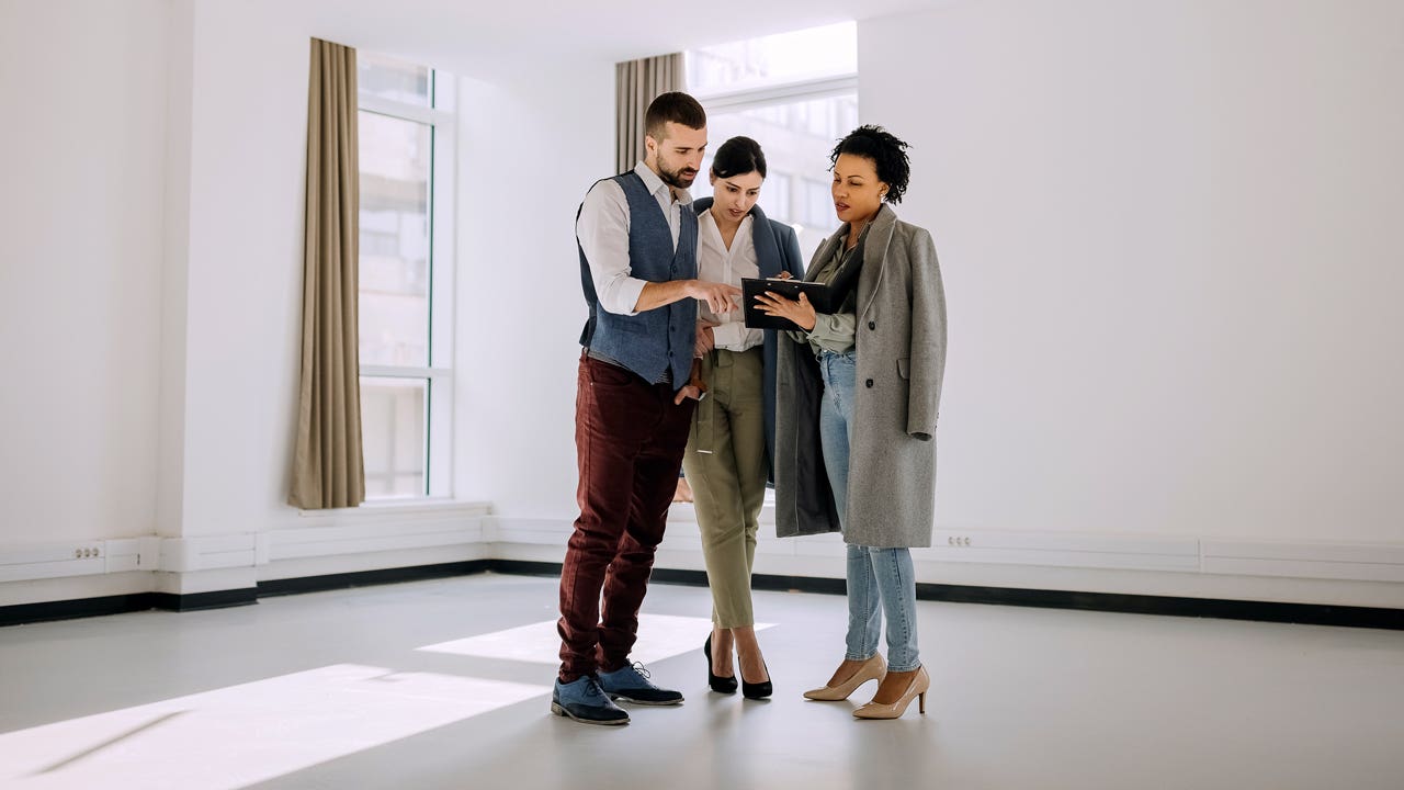 Real estate agent showing a property plans to a couple