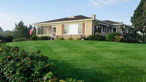 lassic american bungalow from the 60's or 70's with freshly cut lawn.
