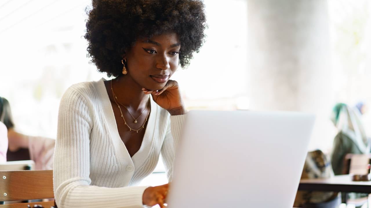 Smiling young Black woman sitting with laptop.