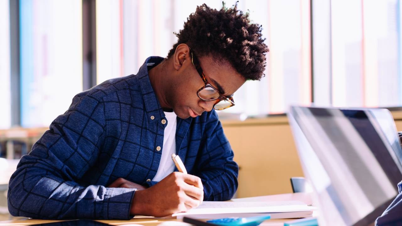 Man writing while sitting at table in library
