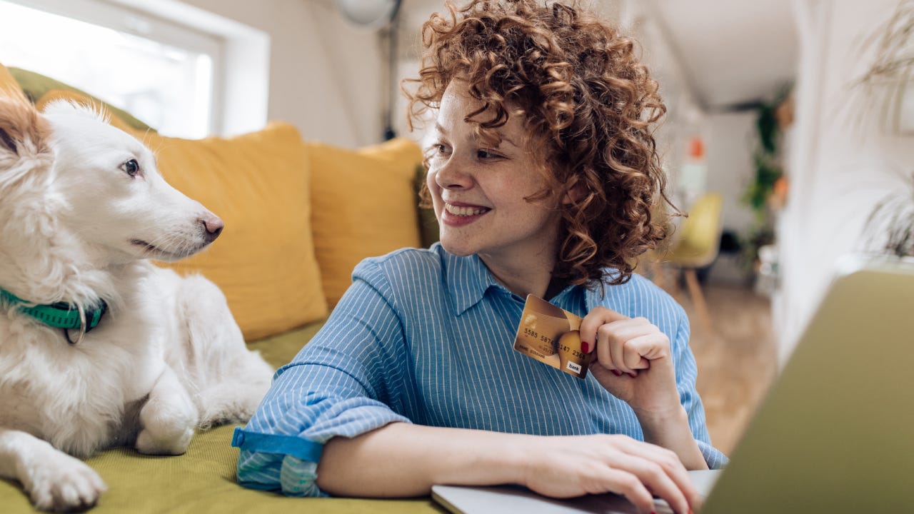 Cute girl enjoying at home with her dog and shopping online