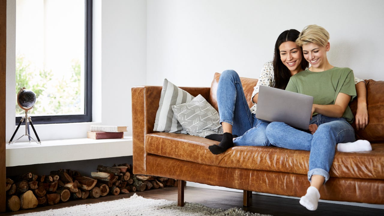 Couple on couch at home looking at laptop