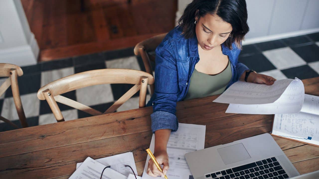 woman using a laptop and going through paperwork while working from home