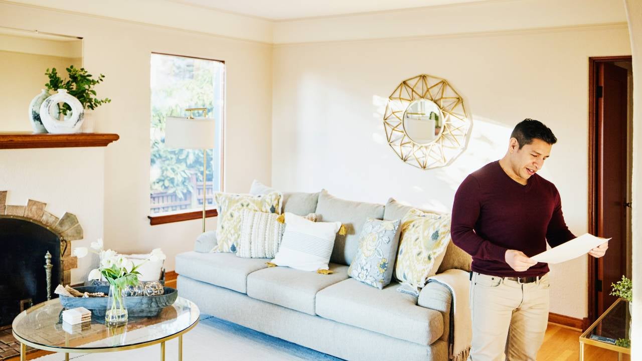Medium wide shot of man looking at sales sheet in home