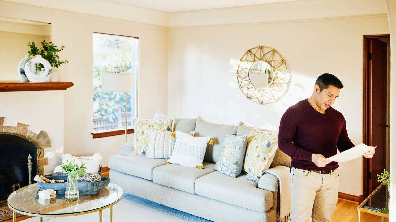 Medium wide shot of man looking at sales sheet in home