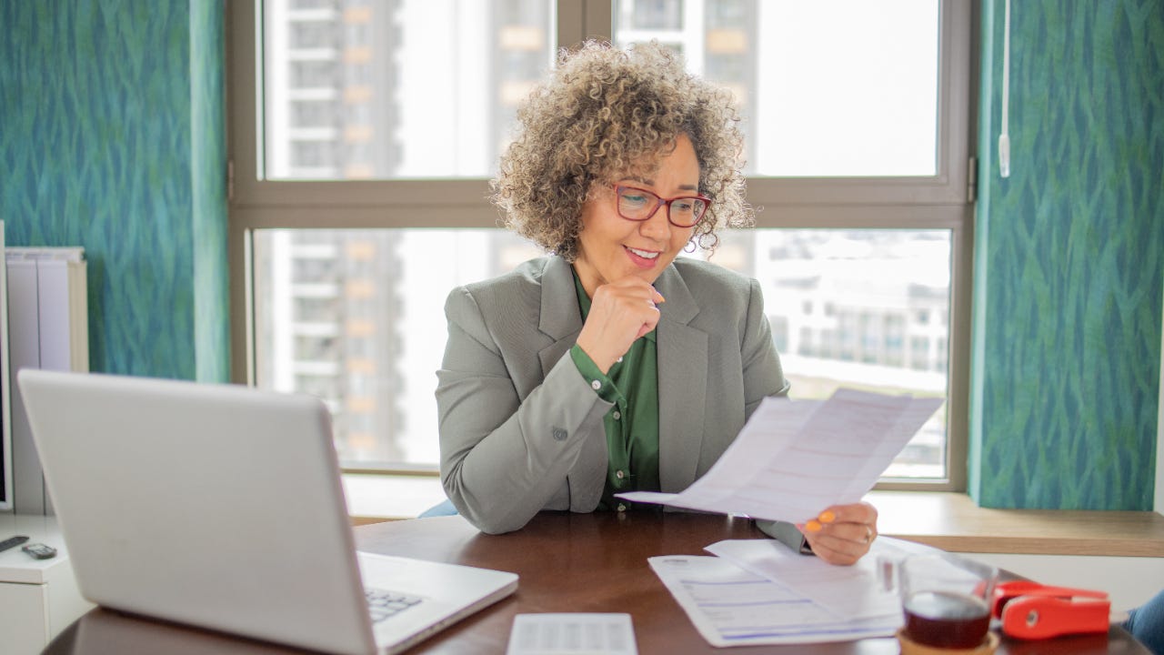 A mature woman reviewing documents in front of a computer