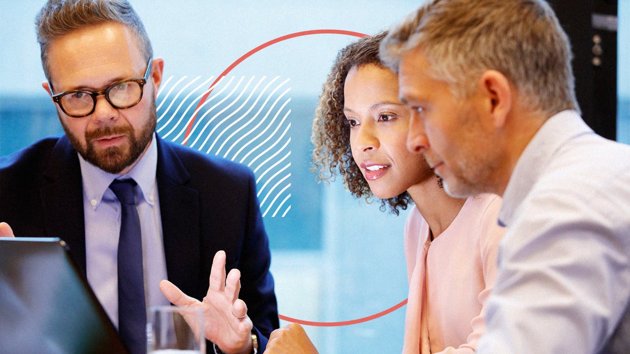 2 men and a woman discuss something at a table.