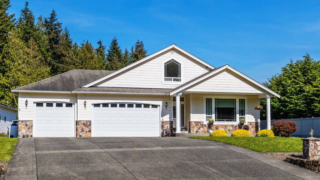 Photo of an American suburban home with a large driveway leading to a three-car garage, on a bright summer day
