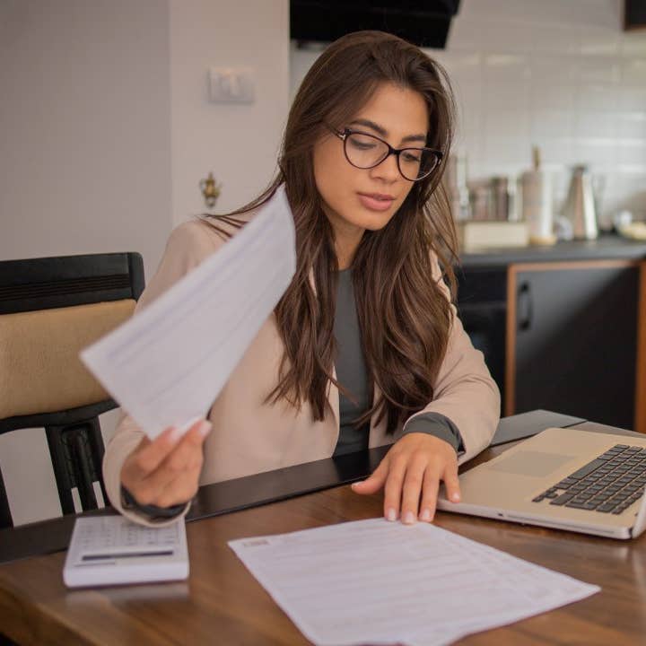 Young woman using calculator while going through bills and home finances