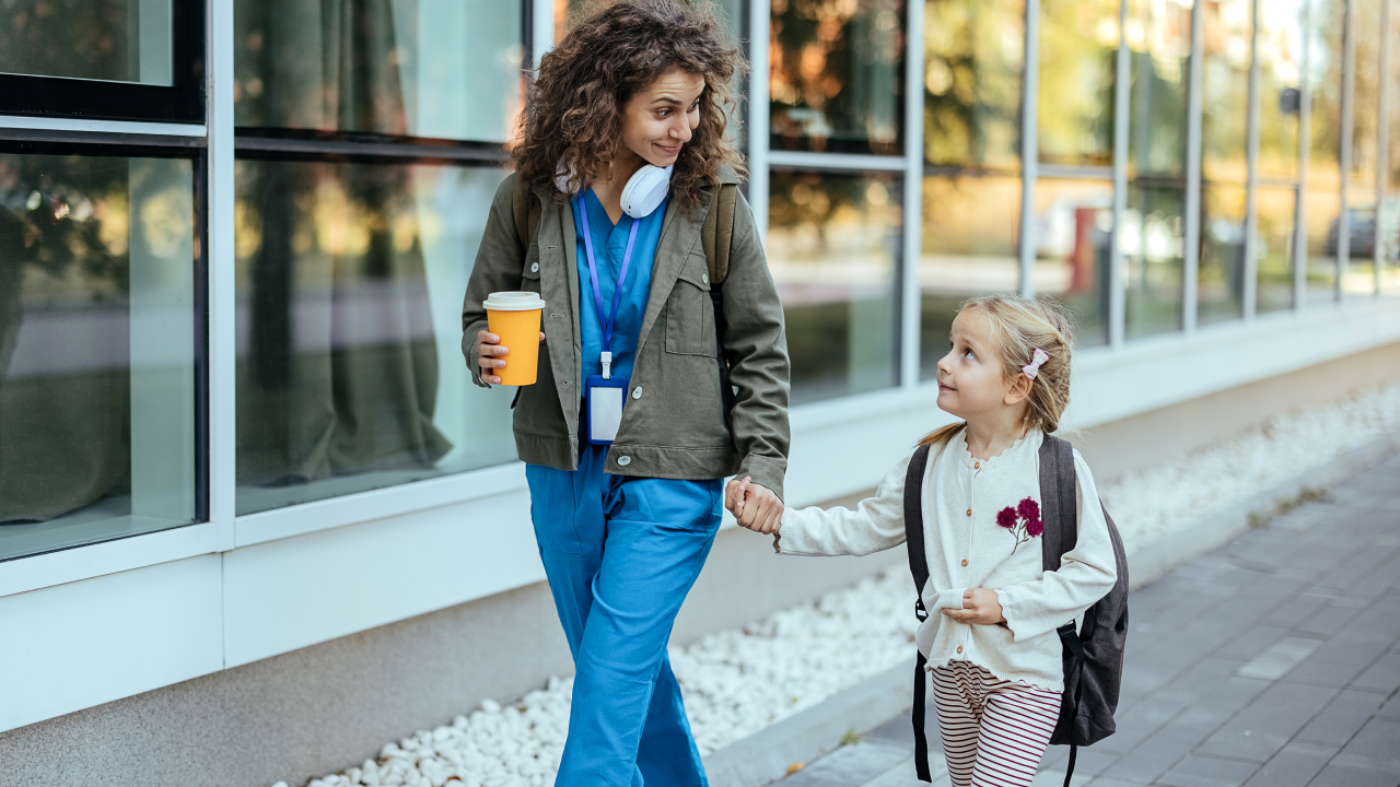 Girl with backpack holding her mother's hand and going to school.