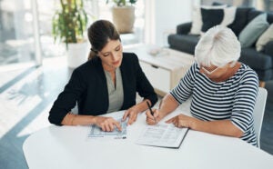 female financial advisor meeting with an elderly female client reviewing her life insurance policy