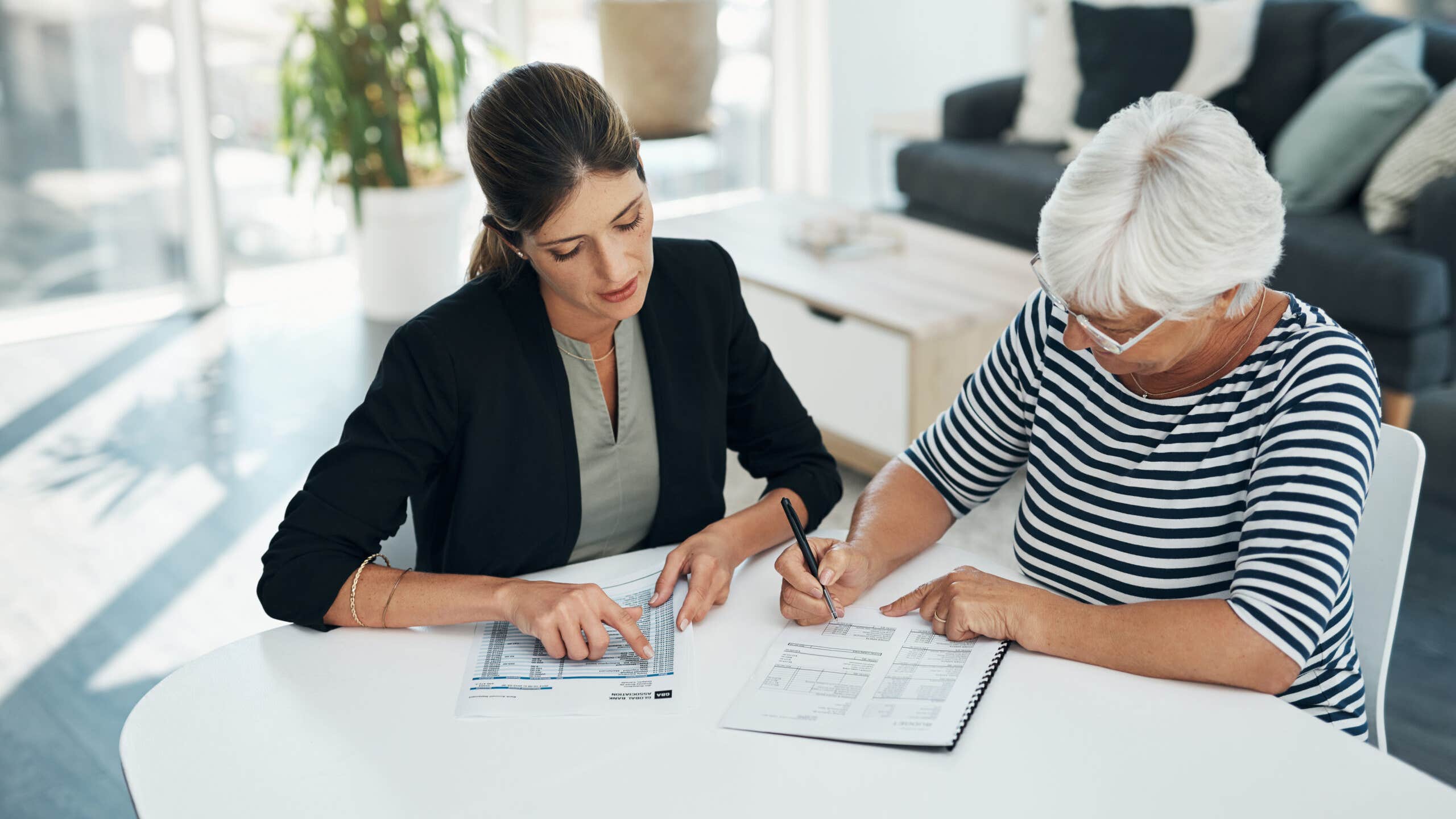 female financial advisor meeting with an elderly female client reviewing her life insurance policy