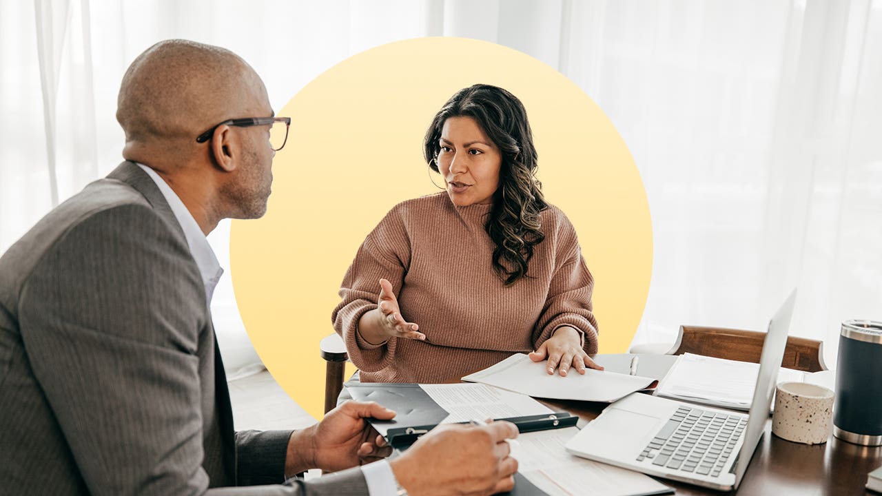 woman with dark features sitting down at a table with a man discussing financials