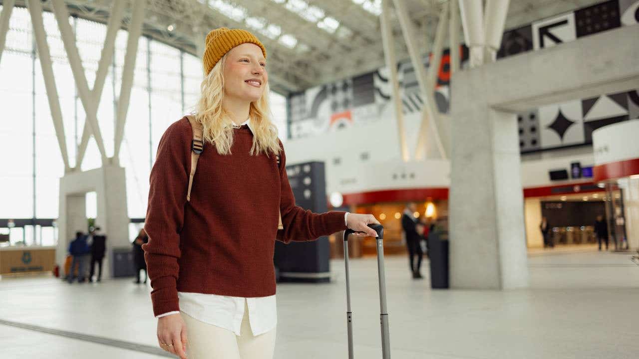 Young happy woman walking through airport.