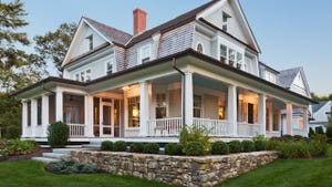 Exterior view of custom built home with exterior lighting and manicured landscaping.