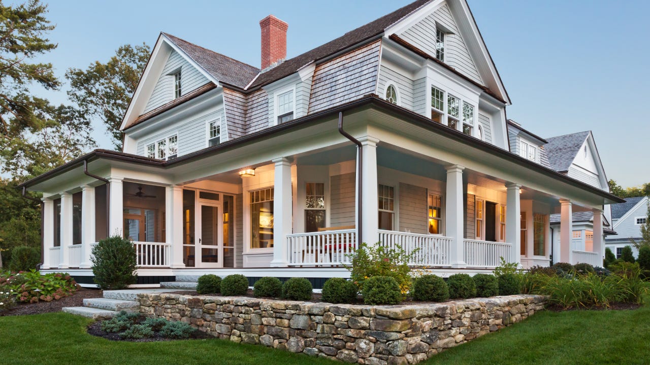 Exterior view of custom built home with exterior lighting and manicured landscaping.