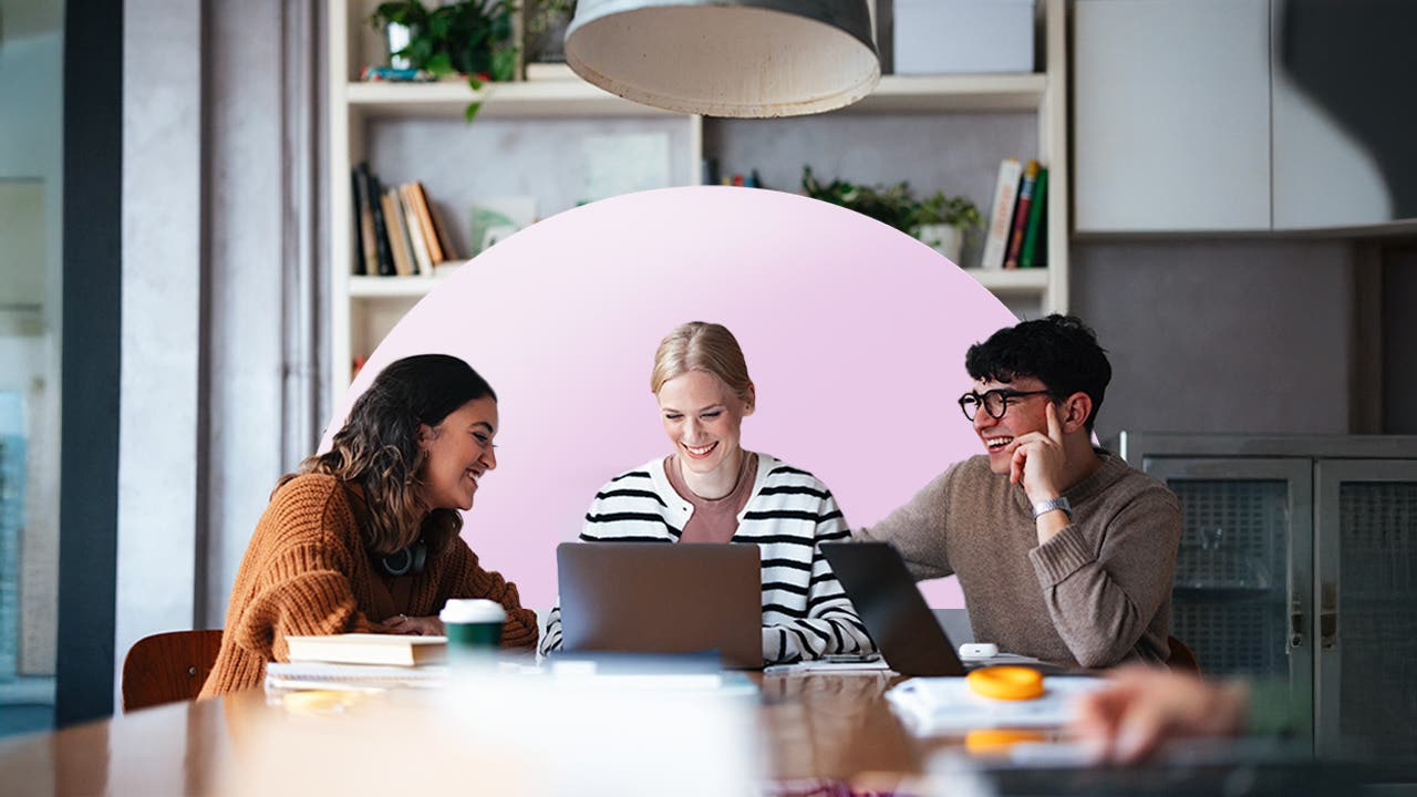 Three colleagues sitting and working together around a laptop.