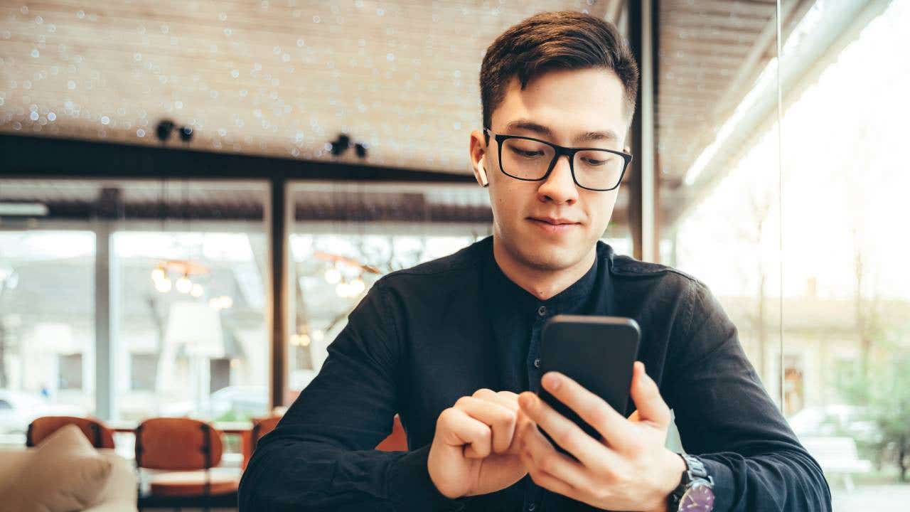 A young man looks at his phone to trade options.