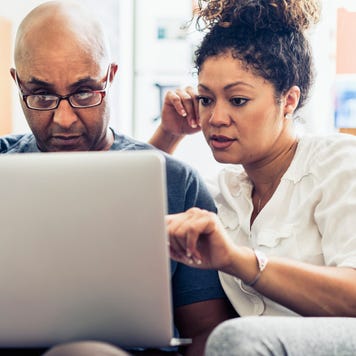 Couple looking at laptop while sitting on sofa at home