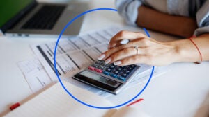 A woman calculates her net worth by adding up her assets and liabilities on a calculator.