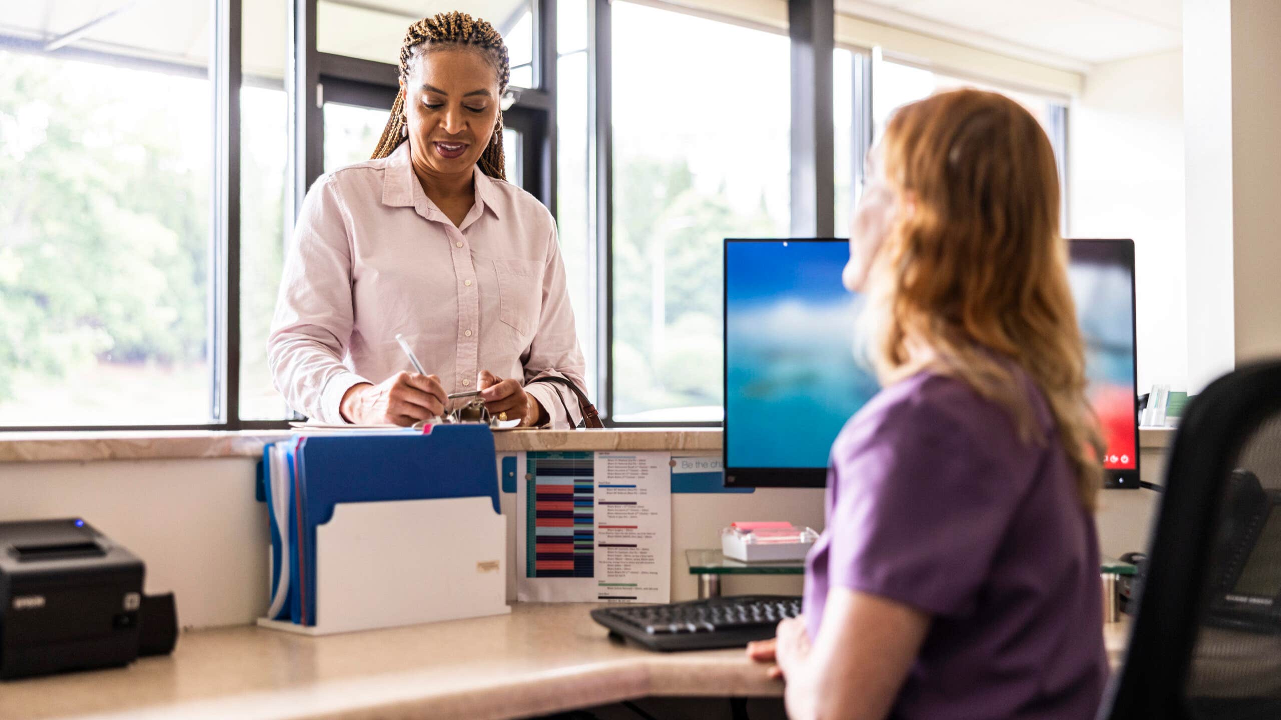 Female patient paying with credit card at doctor's office front desk