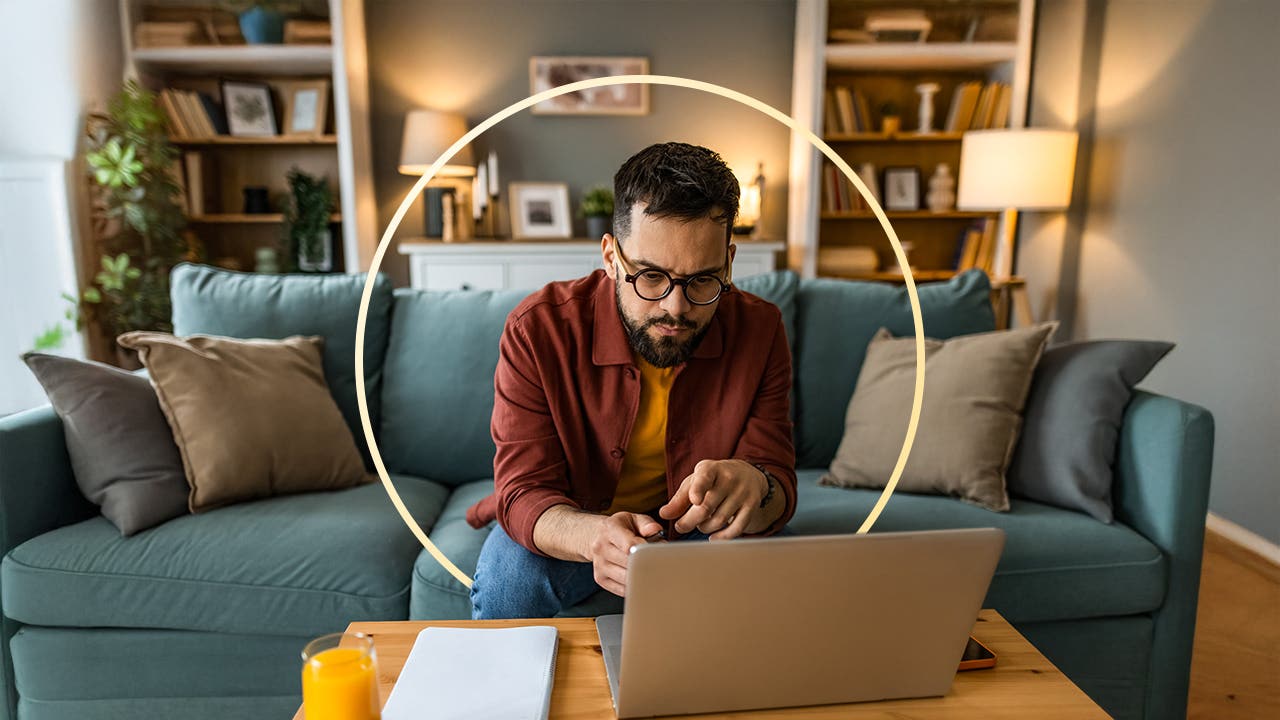 Man sitting on couch and leaning over laptop and doing some work