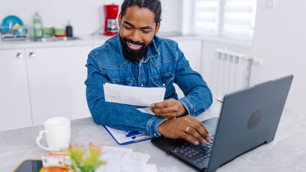 Man sitting at home, at his laptop, working on his finances.