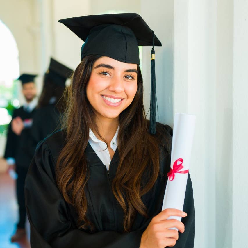 Hispanic woman smiling and making eye contact after getting her university diploma at a graduation ceremony on campus