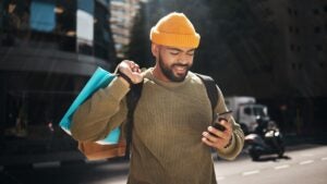 man holding shopping bags and looking at his phone
